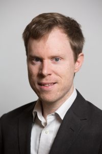 A headshot of Ben Bramble against a light background.