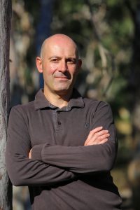 An outdoor portrait of Peter Papathanasiou with crossed arms.