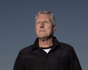 A low angle of Michael Brissenden who is looking off into the distance with a serious expression.