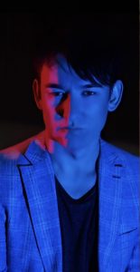 Moody portrait of Wayne Herbert lit by blue and red light.